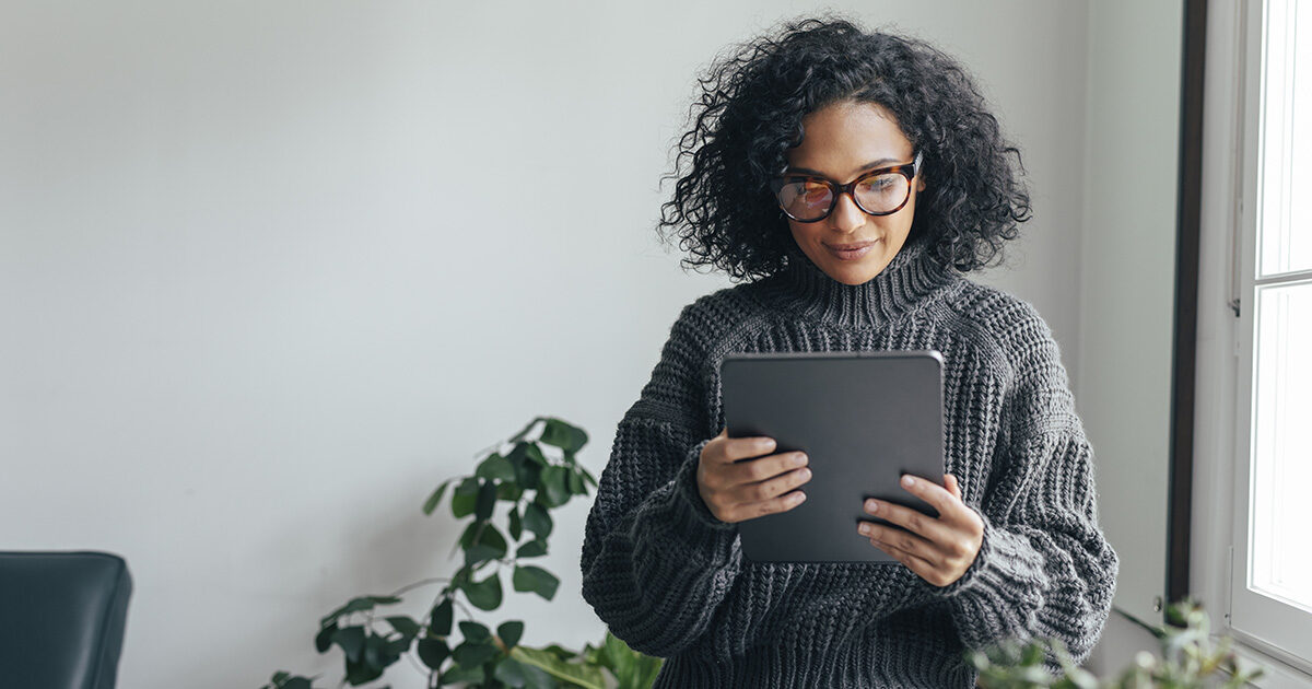 femme métis, trentaine, cheveux noir frisés, tenant une tablette d'ordinateur dans ses mains